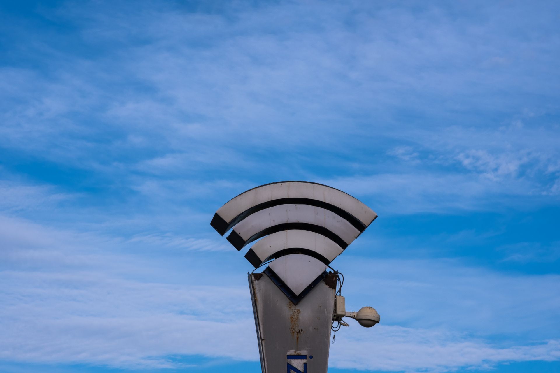 Ein WLAN-Symbol auf einem Mast vor blauem Himmel steht für die drahtlose Vernetzung von Produktionsausrüstung am Filmset.