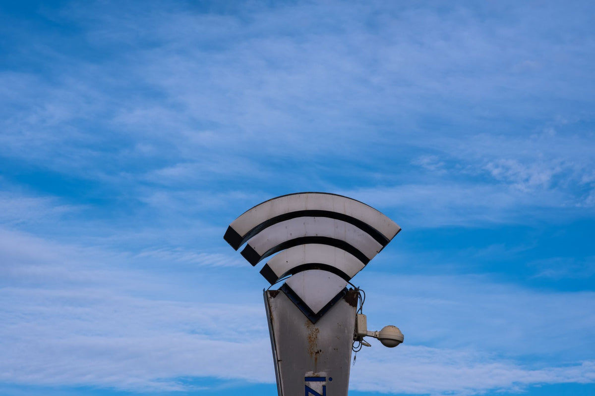 Ein WLAN-Symbol auf einem Mast vor blauem Himmel steht für die drahtlose Vernetzung von Produktionsausrüstung am Filmset.